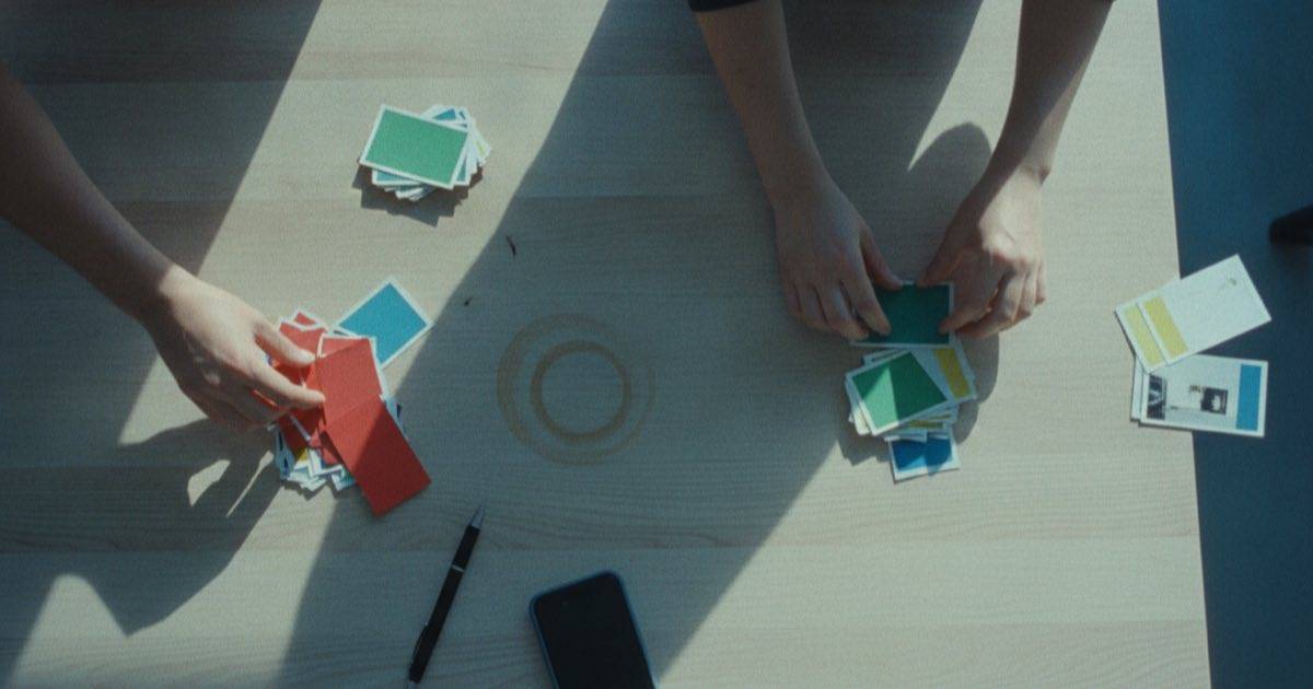 Hands sorting printed content cards into keep and cut piles on a table